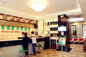 A hotel reception area with a marble counter, a digital screen, and a fire extinguisher. - Pinshang Express Chain Hotel (Dongxing Guomen Port) (Dongxing)