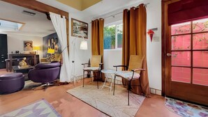 Un salon comprenant un canapé, des fauteuils, une table basse, un tapis et une porte avec une fenêtre.