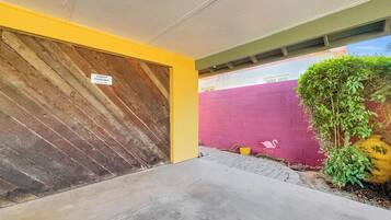 A building entrance with a wooden door, a 'Guest Parking' sign, a red wall, and a small plant.