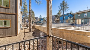 Un barrio residencial con una terraza de madera, un sendero de piedra y una barandilla metálica.