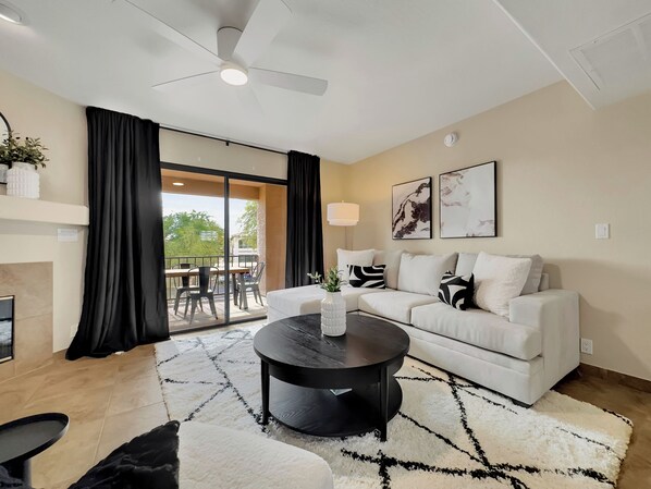 A modern living room with a sofa, coffee table, and a dining area with chairs and a table. - Kings Way #201 Fountain Hills (Fountain Hills)