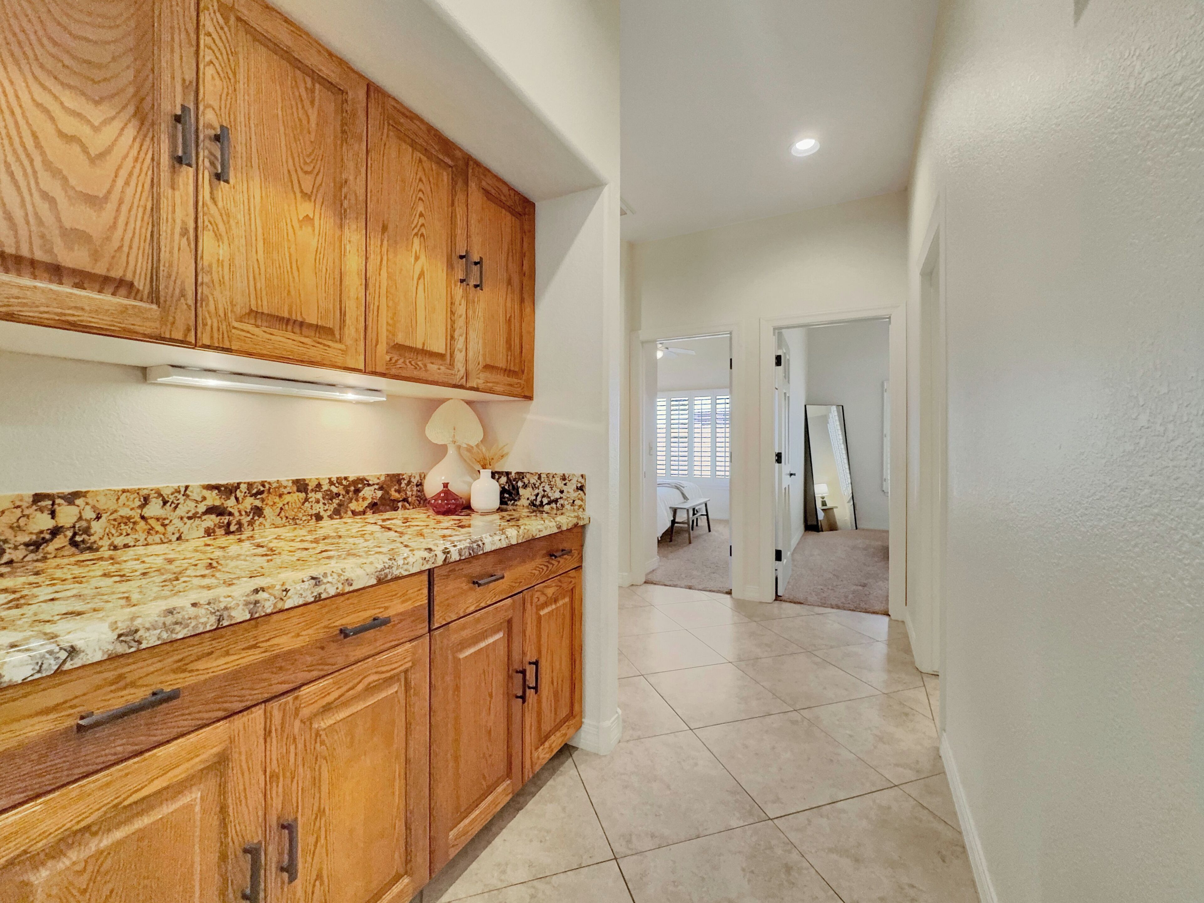 Una cocina con armarios de madera, encimera de granito y vista a otra habitación.