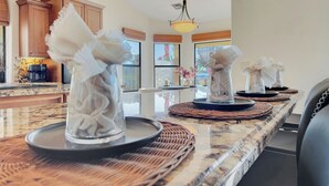 Een keuken met een marmeren aanrecht, houten kastjes en een hangende lamp.