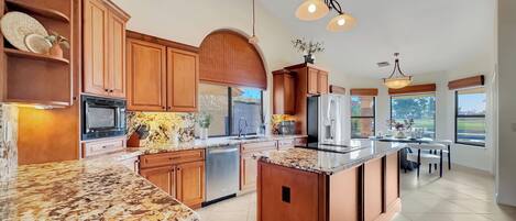 A spacious kitchen with wooden cabinets, granite countertops, and a large island.