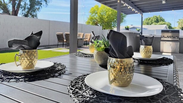 Eine Terrassensitzgruppe mit gedeckten Tischen, inklusive dekorativer Tassen und Servietten.