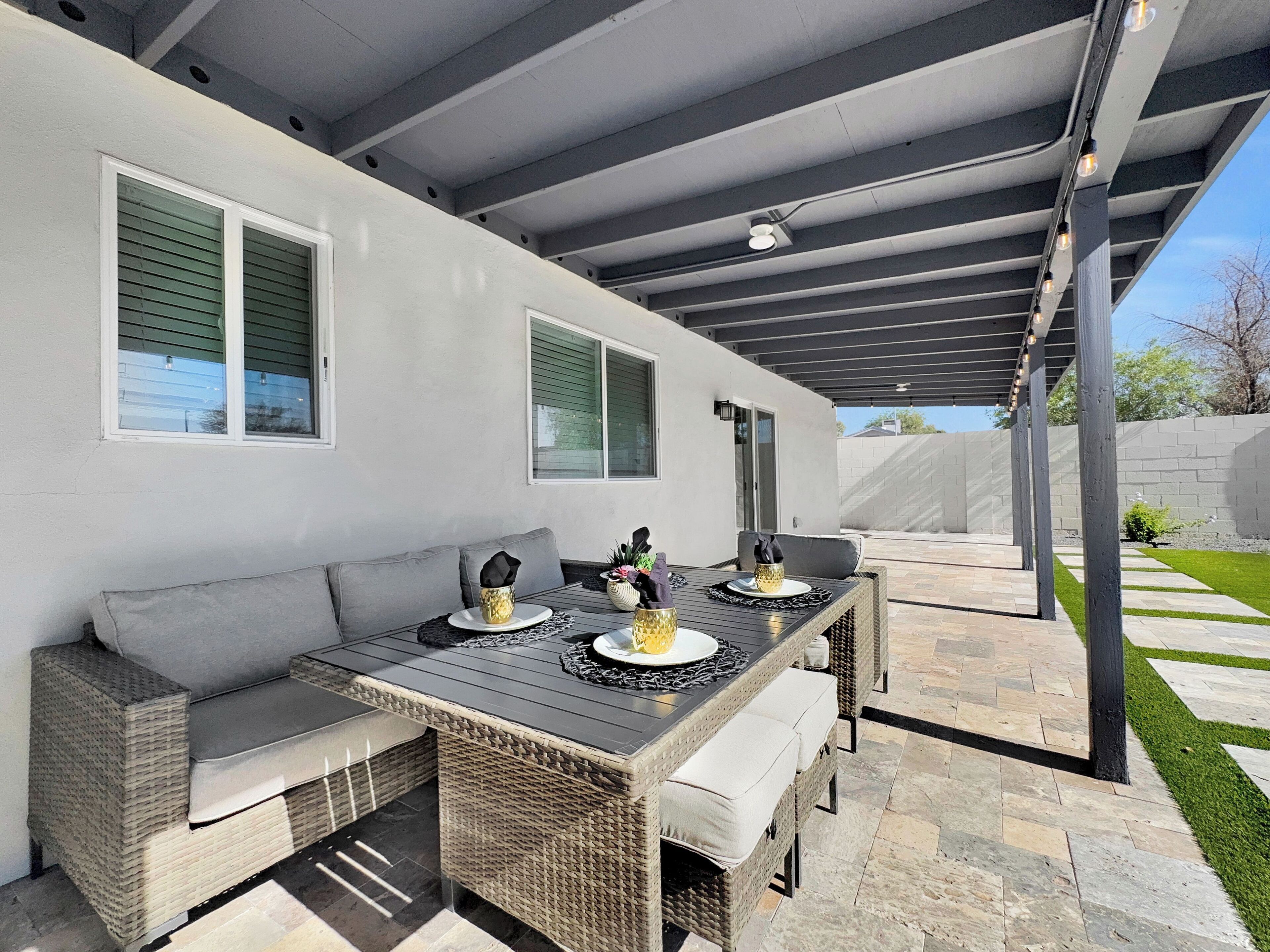 Une terrasse extérieure dotée d’une longue table à manger, de sièges confortables et d’une pergola au-dessus.