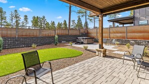 Ein überdachter Patio-Bereich mit Steinmauer, Rasen und Sitzgelegenheiten im Freien.