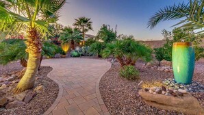 A landscaped garden with palm trees, a winding pathway, and a large decorative vase. - Blackfoot San Tan Valley (San Tan Valley)