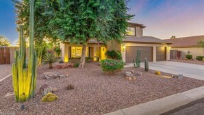 A modern two-story house with a landscaped front yard featuring cacti and a large tree. - Blackfoot San Tan Valley (San Tan Valley)