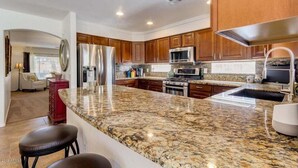 A modern kitchen with granite countertops, stainless steel appliances, and wooden cabinets. - Blackfoot San Tan Valley (San Tan Valley)