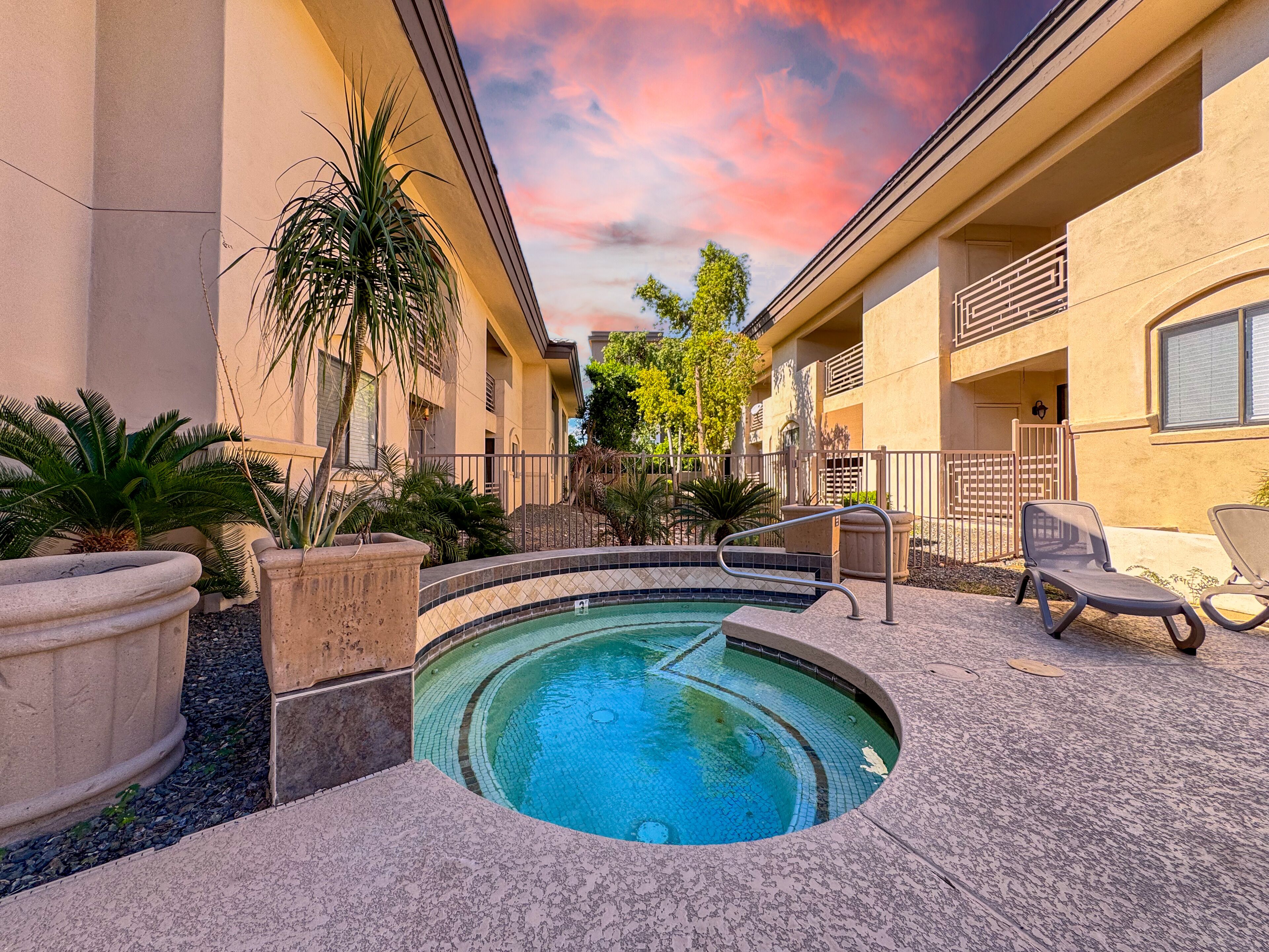 A circular pool with a tiled edge, surrounded by a paved area with lounge chairs and potted plants.