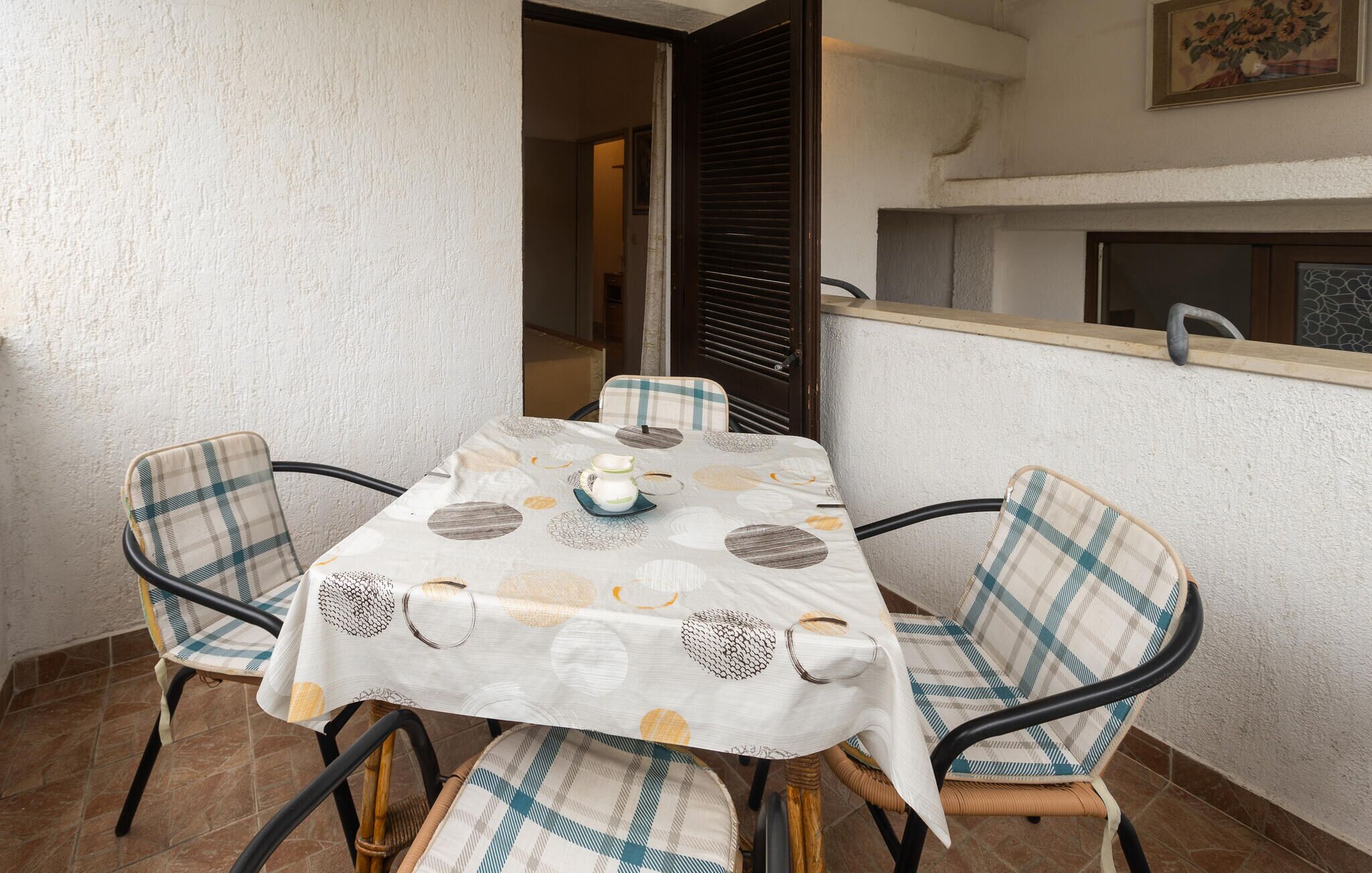 Un coin repas avec une table recouverte d’une nappe à motifs, entourée de quatre chaises dotées de coussins à carreaux.