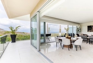 Relax in a spacious living area with a sliding door leading to a balcony and a dining area with a round table and comfortable seating.
