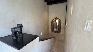A narrow hallway with a black countertop on the left, a decorative mirror on the right, and a light switch on the wall. - Casa Bovedas Collection by Ritzy Group (Cartagena de Indias)
