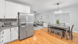 Una cocina moderna con armarios blancos, un refrigerador de acero inoxidable y un tostador empotrado.