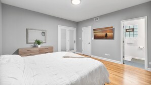 Un dormitorio con una cama grande, un aparador, un cuadro y una puerta con ventana.