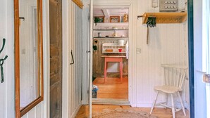 A narrow hallway with a wooden door, a white radiator, and a small table with a chair. - Pet friendly home in Malmbäck with WiFi (Malmbäck)