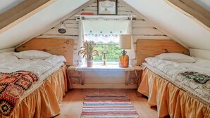 A cozy attic bedroom with two beds, a window with a view, a lamp, and a small table with a plant. - Pet friendly home in Malmbäck with WiFi (Malmbäck)