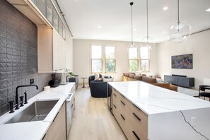 A modern kitchen with a large island, built-in appliances, and a dining area with a sofa and table.