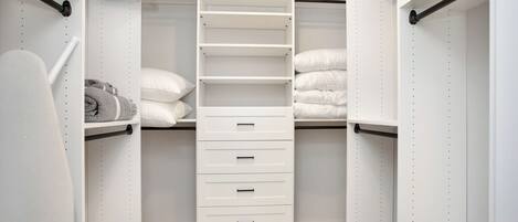 A walk-in closet with white shelving, drawers, and hanging space.