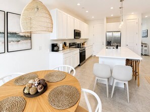 A modern kitchen with white cabinetry, stainless steel appliances, and a central island with seating.