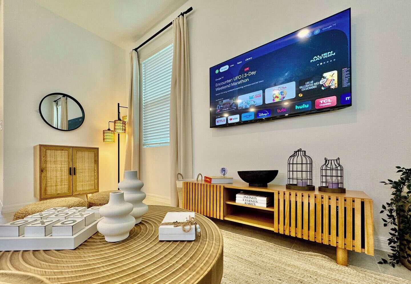 A modern living room with a flat-screen TV mounted on the wall displaying a live event.