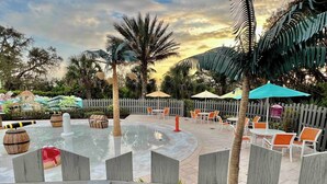 An outdoor patio area with a circular water feature, seating arrangements, and a wooden fence.