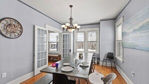 A dining room with a long table, chairs, a chandelier, and a clock on the wall. - 6 Min to Ark! Accommodates 17! (Williamstown)