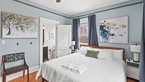 A bedroom with a large bed, a wooden bench, and artwork on the walls. - 6 Min to Ark! Accommodates 17! (Williamstown)