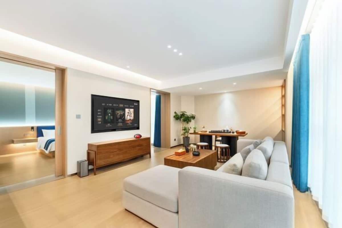 A modern living room with a sofa, coffee table, and a TV mounted on the wall.