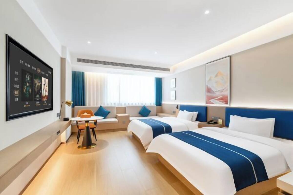 A hotel room with two beds, a desk, and a seating area.