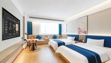 A hotel room with two beds, a desk, and a seating area.