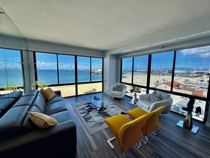A spacious living room with a large window overlooking a beach and cityscape. - Beachfront on the 9th floor, 2 bedroom, 2 bath, stunning ocean and City views. (Long Beach)
