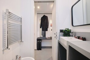 Un baño moderno con un perchero, un lavabo, un espejo y una maleta.