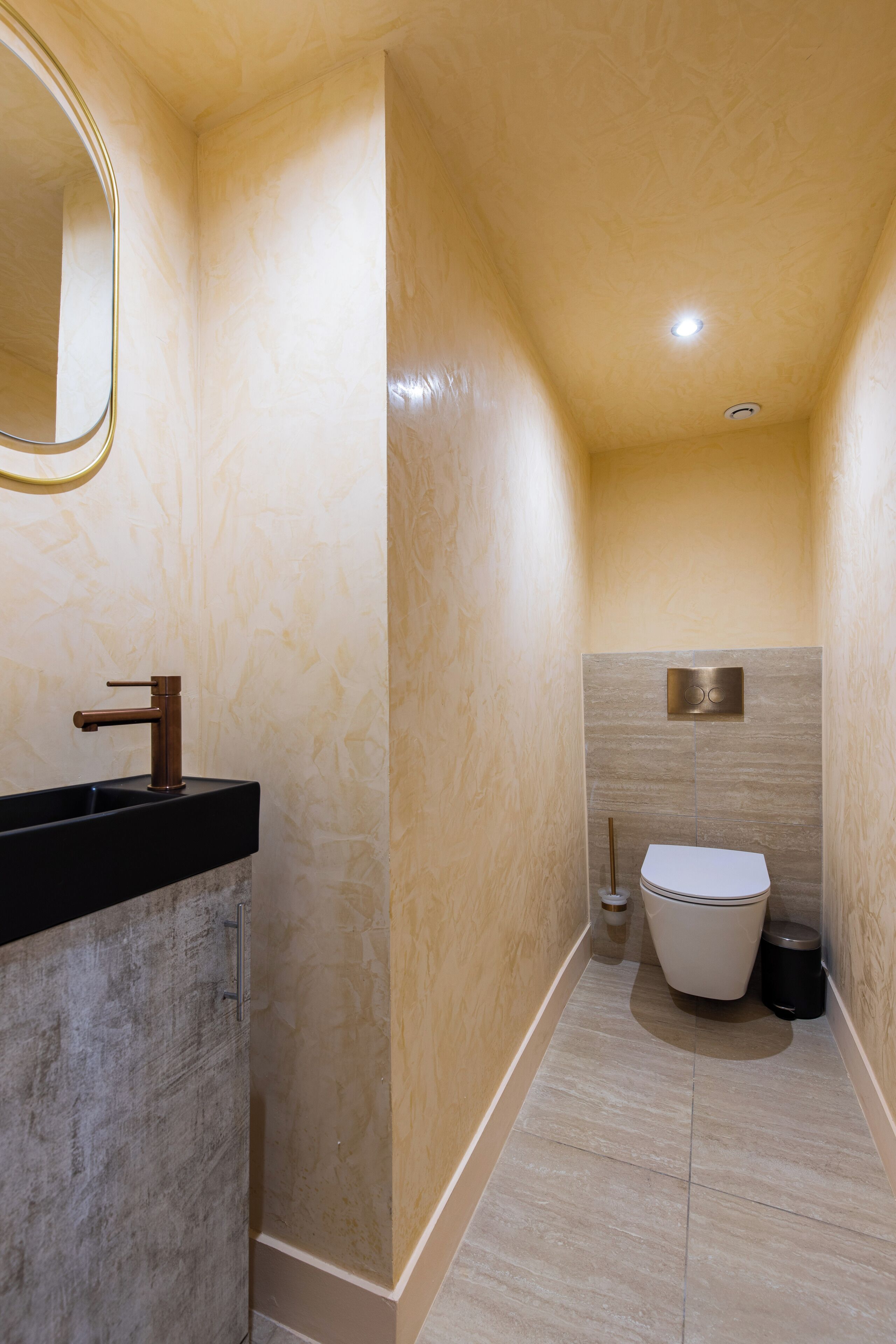 Une petite salle de bain avec un lavabo noir, des toilettes blanches et un miroir.