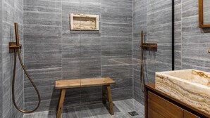 A modern bathroom with a marble sink, a wooden bench, and a shower with a handheld showerhead. - Hotel My Paris - Grands Boulevards (Paris)