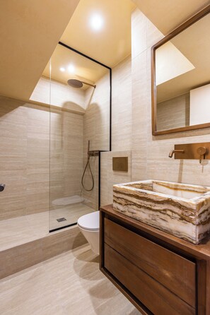A modern bathroom with a glass-enclosed shower, a marble sink, and a large mirror.