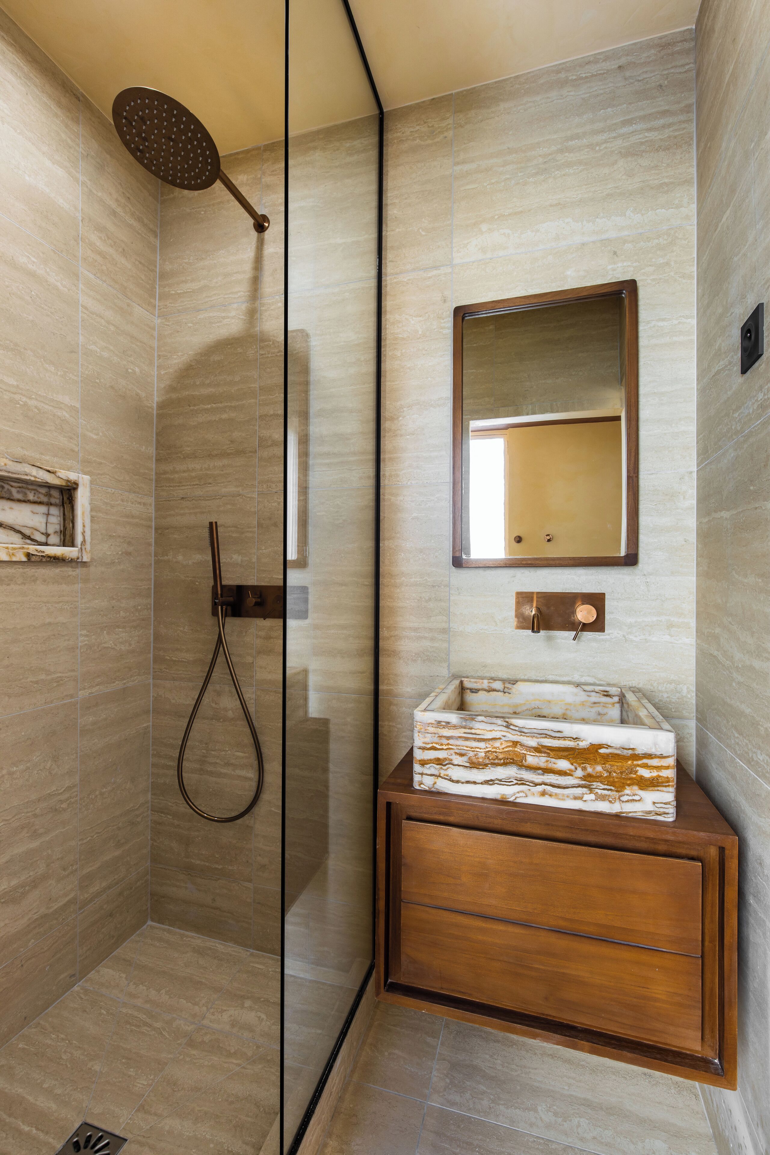 A modern bathroom with a glass-enclosed shower, a marble sink, and a wooden vanity.