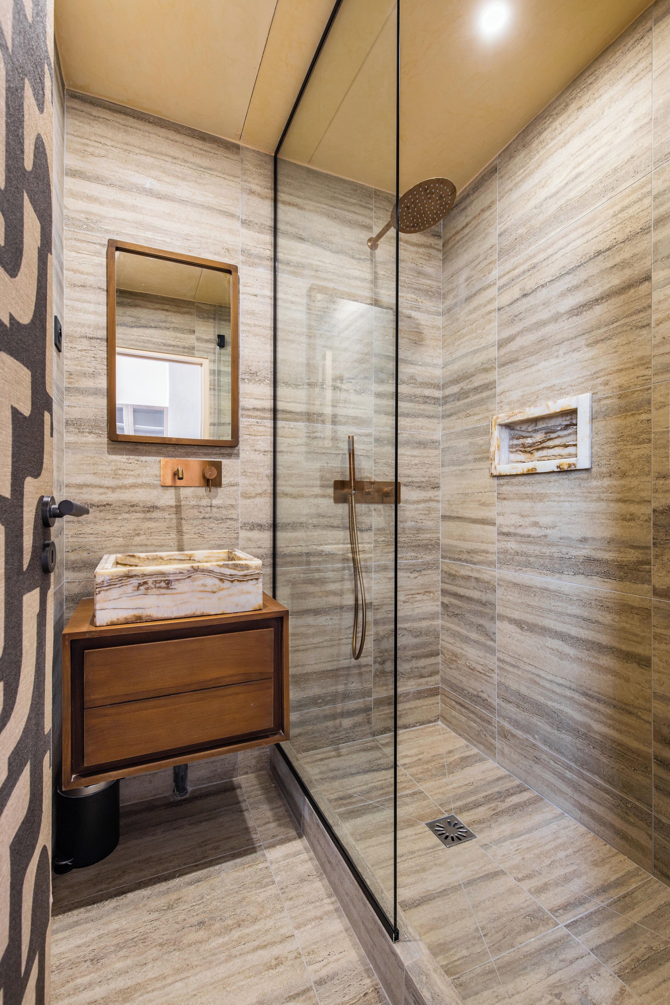 Une salle de bain moderne avec une douche à parois de verre, un meuble-lavabo en bois avec un vasque en marbre et un miroir au-dessus du meuble-lavabo.