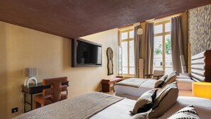A hotel room with two beds, a desk with a chair, a TV, and a window with curtains. - Hotel My Paris - Grands Boulevards (Paris)