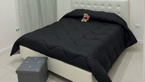 Une chambre à coucher avec un lit, une petite table de chevet et une fenêtre avec des rideaux.
