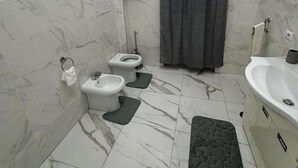 Une salle de bain avec deux toilettes, une baignoire et un lavabo.