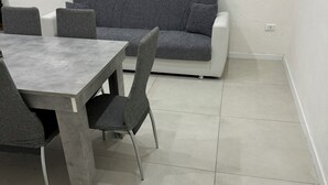 Un coin repas avec une table et des chaises, un canapé gris et un mur blanc.