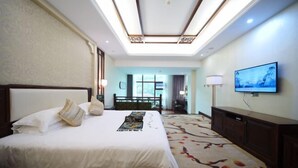 Habitación de hotel con una cama grande, un televisor de pantalla plana montado en la pared y vistas al exterior a través de la ventana.
