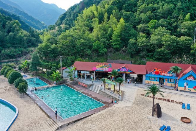 Un resort con piscina, zona de playa y un edificio de fachada colorida.