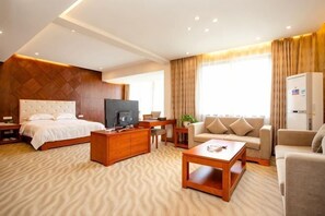 A hotel room with a bed, a TV, a sofa, a coffee table, a desk, and a refrigerator. - Niujiao Resort (Wuyi)