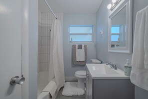 Une salle de bain avec douche, toilettes, lavabo et une fenêtre.