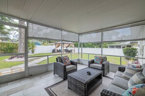 A covered patio area with wicker furniture, a coffee table, and a view of the backyard. - Spacious Family Home Near Hospitals, USF, & Parks (Tampa)