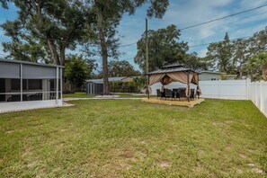 Un jardin avec un patio couvert, un abri de jardin et une maison.