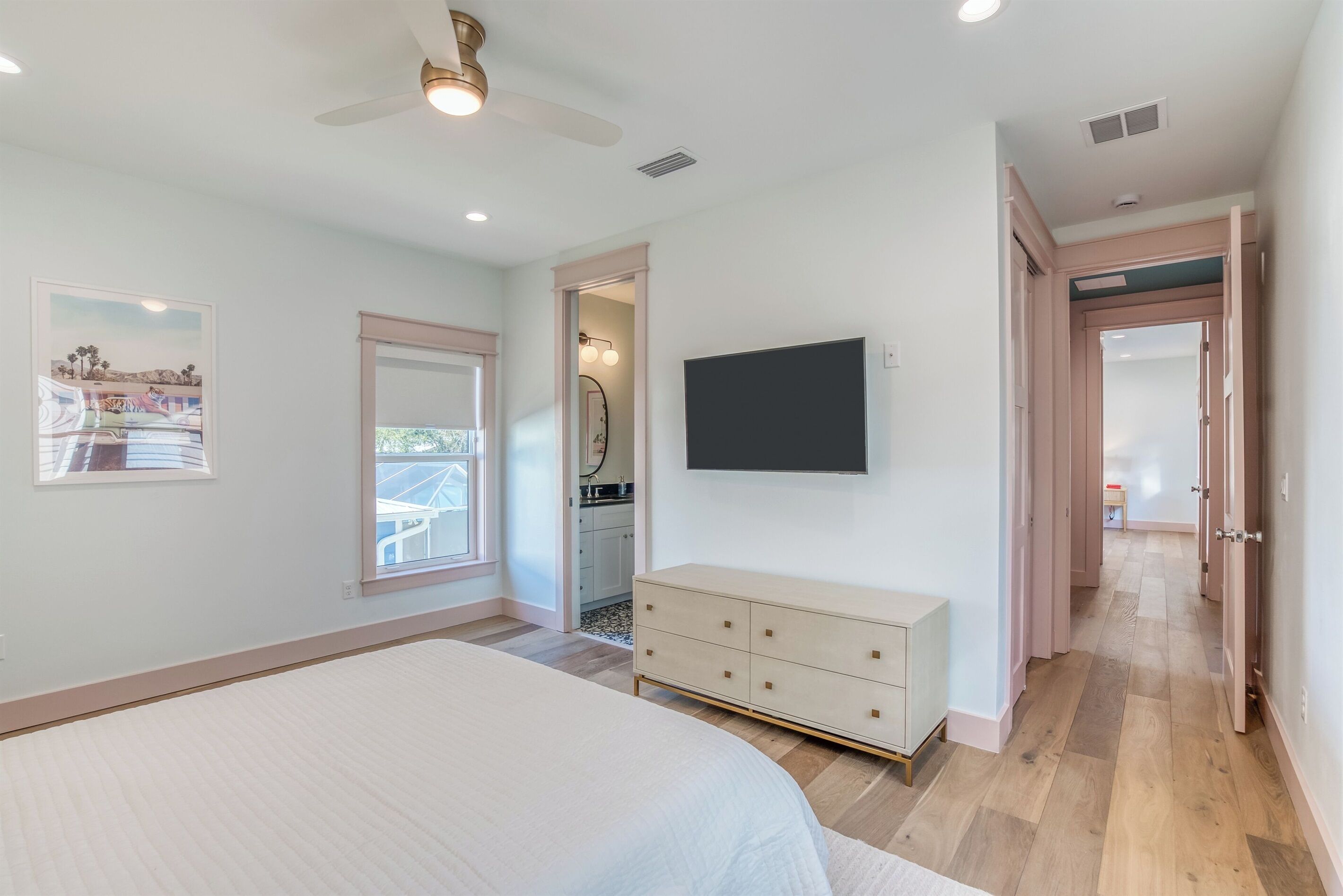 A bedroom with a bed, a dresser, a TV, and a ceiling fan.